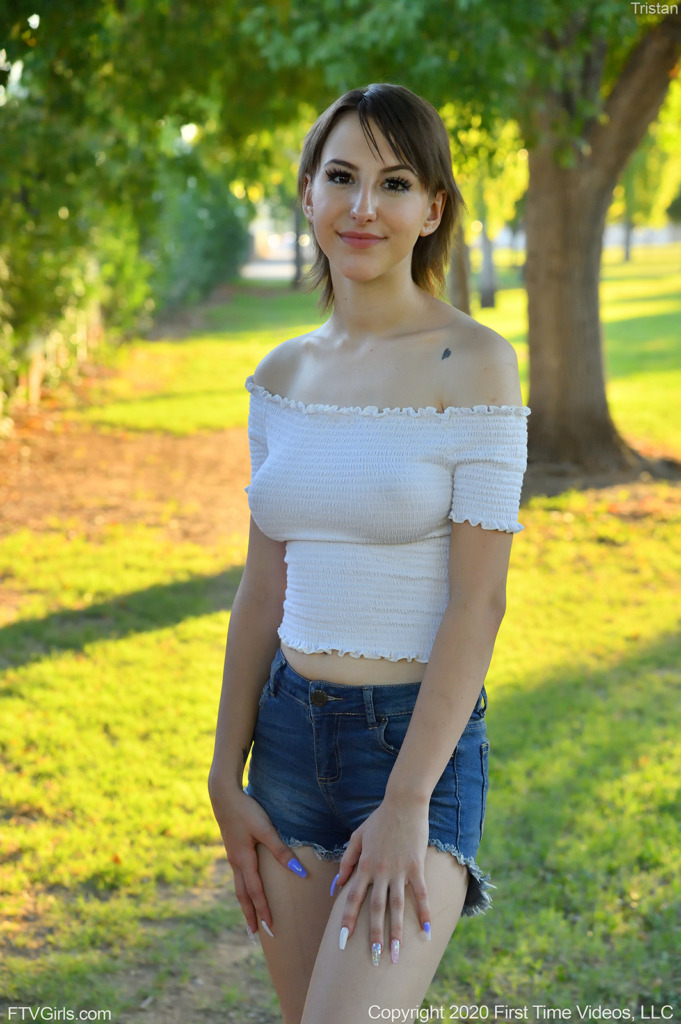 teen pornstar Tristan FTV is standing wearing her white dress and blue denim shorts and is non nude while her nipples are a little bit seen in Play In The Outdoors